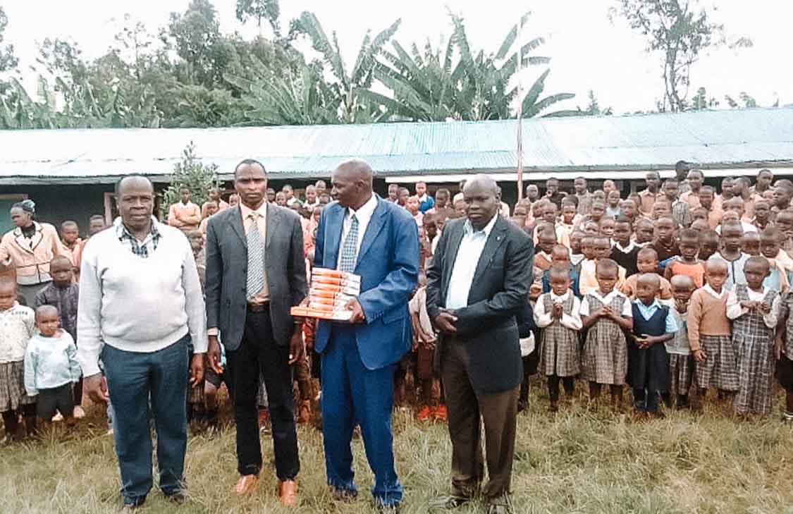 Four men receiving Bibles in front of a group of children