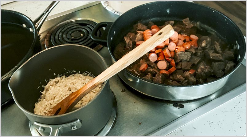 A photo of cooked rice in a pan and the meat mixture in a skillet on the stove
