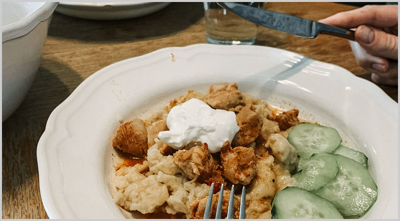 A photo of a plate of Chicken Paprikas and Cucumber Salad