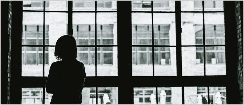 a photo of a woman staring out a window
