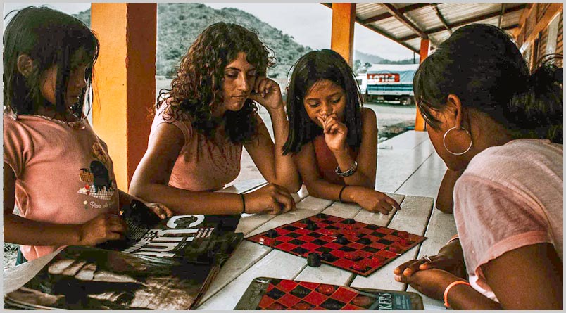 A photo of volunteers playing Checkers with children in Honduras.