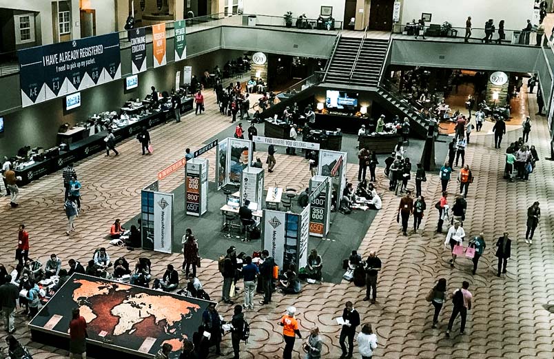 A large conference room with people visiting mission booths