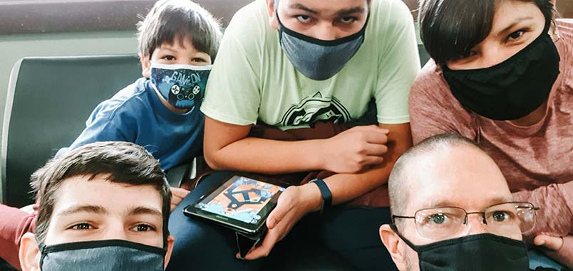 A family wearing masks in an airport waiting area