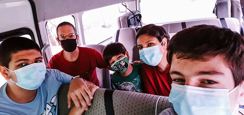 A family wearing masks in an airport shuttle