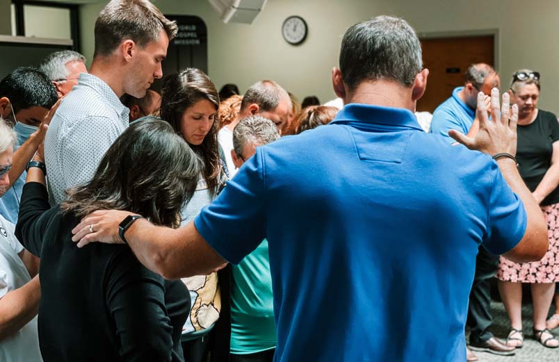 A group of men and women laying hands on others and praying.