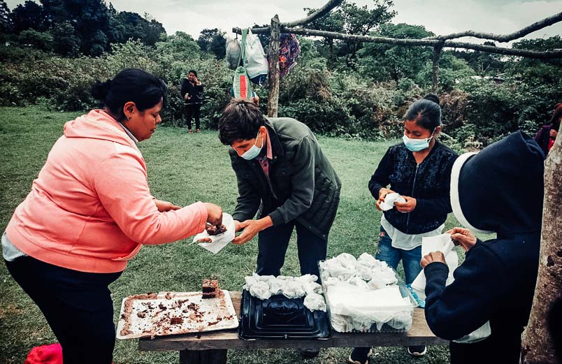 Isaac Jines being served cake by Honduran women at an outdoor gathering.