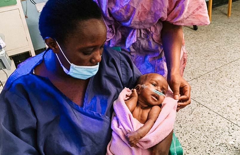 A woman holding an alert baby who is using oxygen