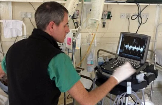 A photo of Heath using the new ultrasound machine to evaluate a post-operative cardiac patient.