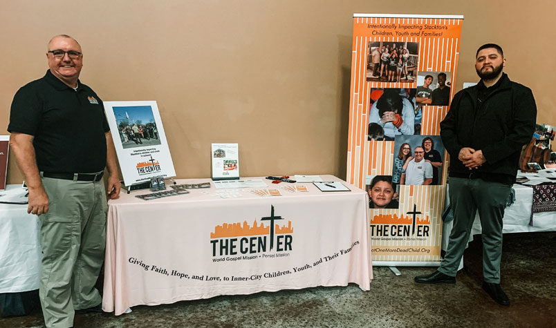 Bob and Napoleon standing next to a table, representing The Center at the “Mission Possible” conference. 