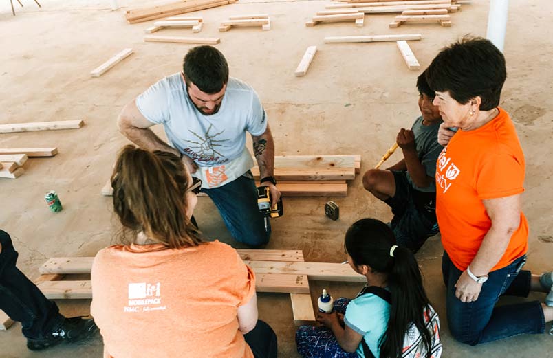 Kids and team members work together to build some benches.