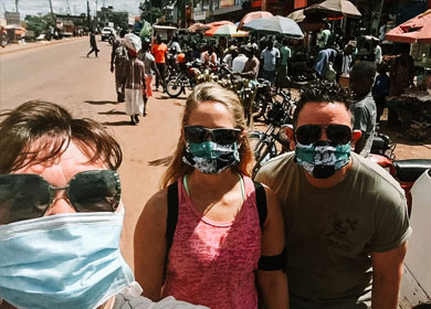Justin and Debbie wearing masks and sunglasses on a busy street in Uganda