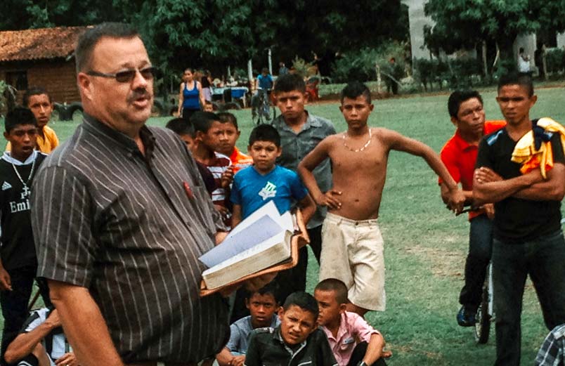 Larry Overholt speaking to a group of kids during a sporting event 