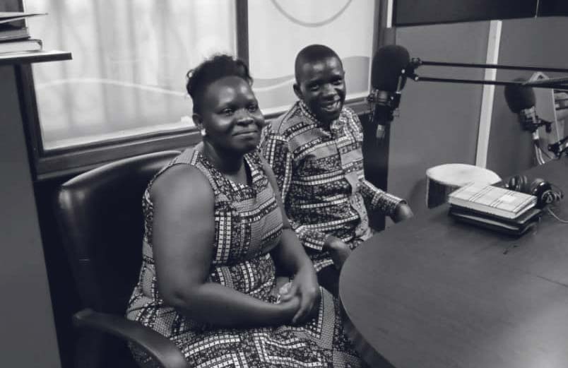 A husband and wife sitting in a radio studio, smiling