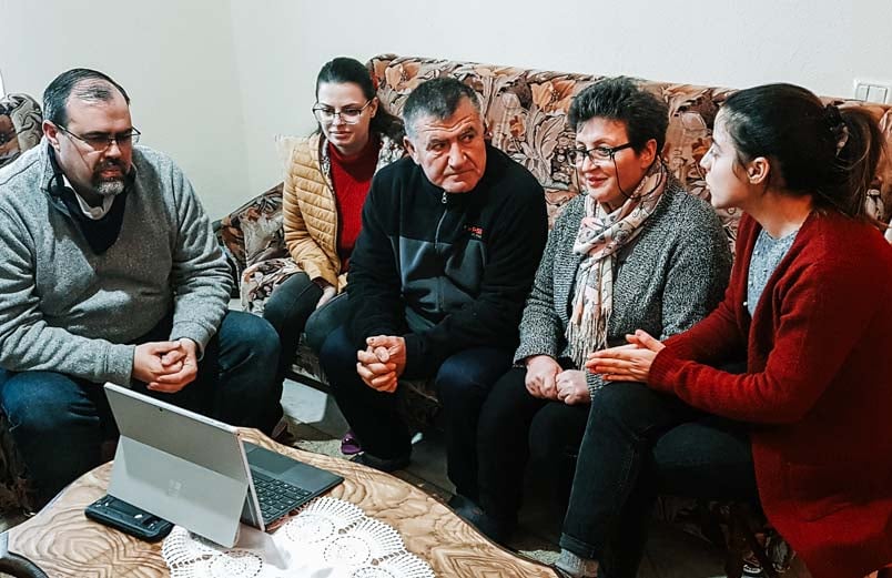 The daughter translates what is being said in English for her parents during the Zoom meeting in their home.