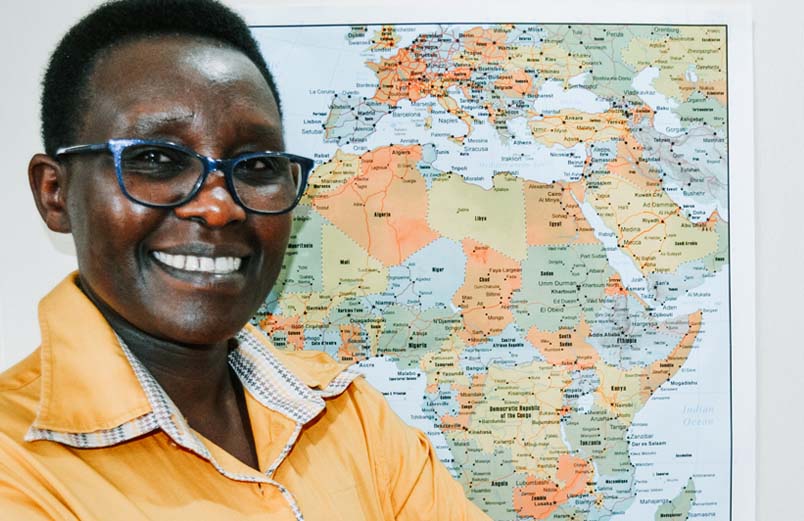 A smiling woman standing in front of a map of Africa