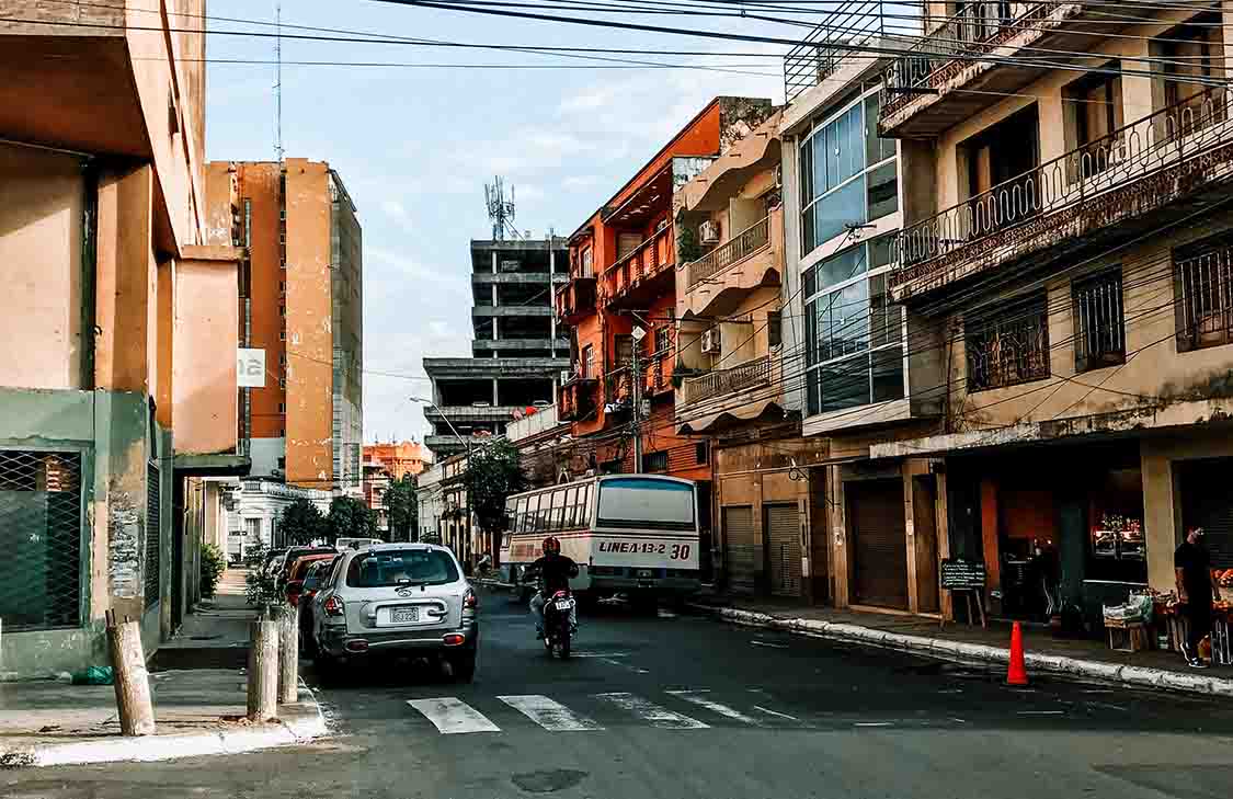 A busy street in Paraguay A busy street in Paraguay with cars, a bus, and a person riding a motorcycle